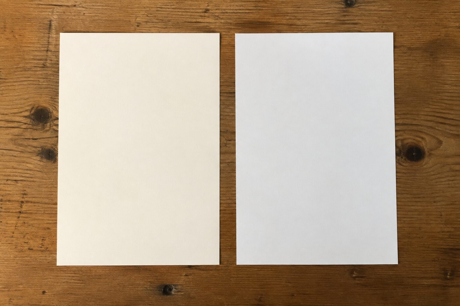 Twee blanco vellen fotopapier naast elkaar op een houten tafel